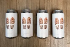 Happy Hour 27 Ankle Buster Blonde 4 Pack including four cans of clean and refreshing blonde ale with orange boot-print design and light malt sweetness.