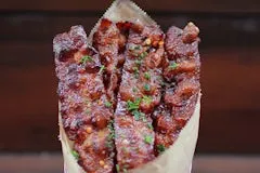 Bacon Candy glazed with brown sugar, red pepper flakes, and black pepper, giving a caramelized and spicy finish.