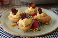 Crispy Deviled Eggs topped with smoked paprika, creamy yolk filling, and pieces of bacon candy.
