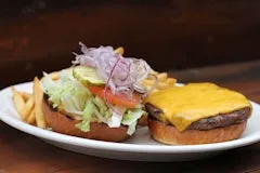 Catering 33 Cheeseburger with melted cheddar cheese served on a toasted bun, topped with lettuce, tomato, pickles, and sliced onions, alongside golden French fries.