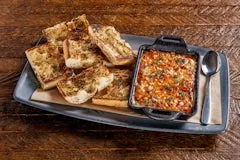 Happy Hour 14 Hot Honey Feta Dip topped with herbs and honey, served with grilled herb French bread for dipping.