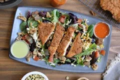 Southern Fried Chicken Salad with crispy chicken strips, mixed greens, walnuts, cornbread croutons, cheese, tomatoes, and dressings.