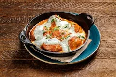 Happy Hour 13 Tikka Masala Meatballs made with tender chicken meatballs in spiced tomato curry sauce, topped with cucumber drizzle and cilantro.