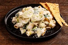 Home 21 Rigatoni pasta tossed in lemon cream sauce with zucchini, baby spinach, spring peas, romano cheese, creamy burrata cheese, basil oil, and toasted bread slices