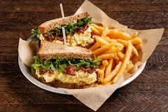 Home 25 Multigrain sandwich layered with creamy egg salad, bacon candy, baby greens, spring onion aioli, served with crispy fries on the side